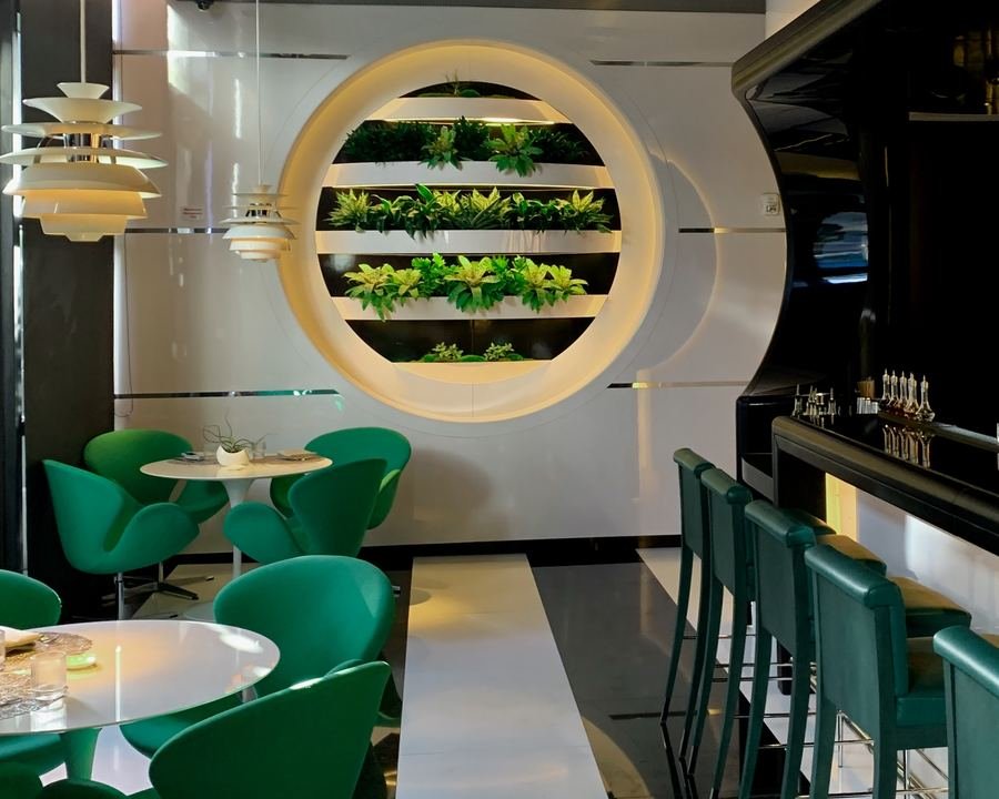 A biophilic bar lounge framed by a circular green wall window