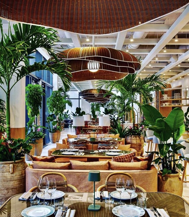 Conservatory-style dining room with a statement pendant and palms